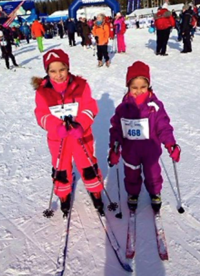 To blide jenter ca 6-8 år på ski med nummerlapp foran på parkdressene
