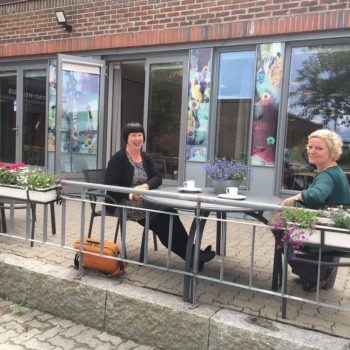 To damer sitter ved et bord utenfor en kafé