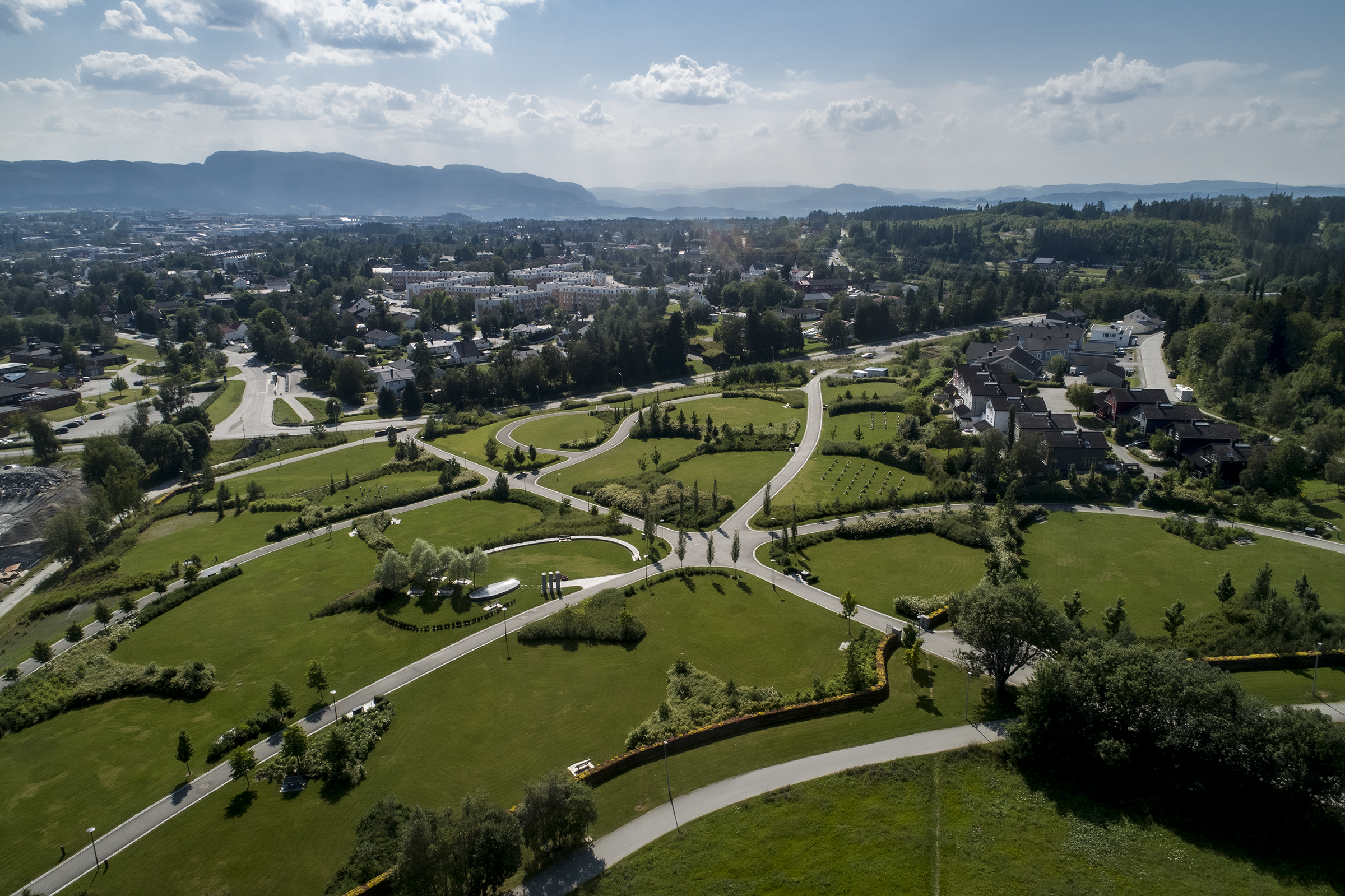 Dronebilde av stort parkanlegg med geometriske gangveier i sol